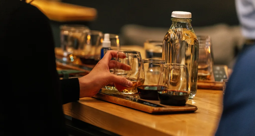 Person extending hand toward wine glasses on a wooden tray