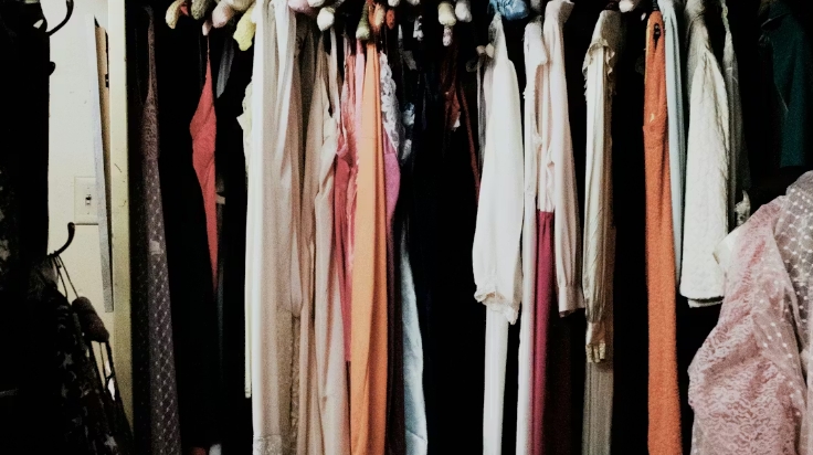 Colorful assortment of dresses hanging in a dimly lit closet