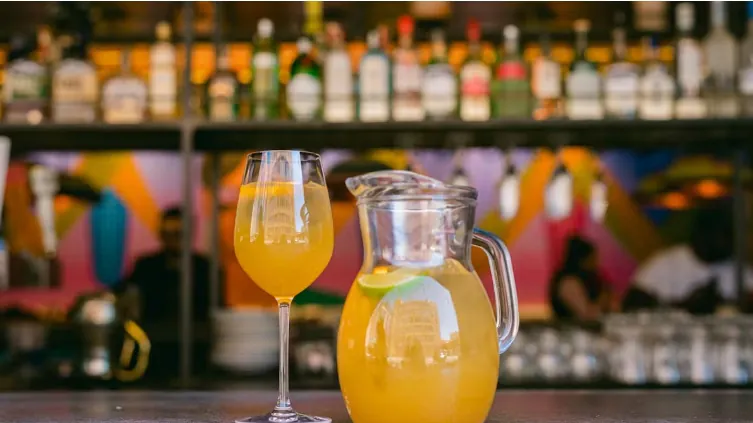 Glass and pitcher of orange juice on bar counter