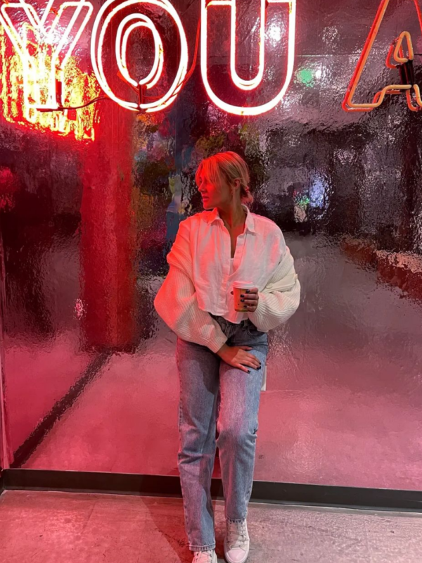 woman standing in front of neon sign in the alley at dairy block in denver