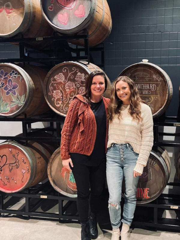 two friends standing in front of wine barrels at Blanchard Family Wines at Dairy Block