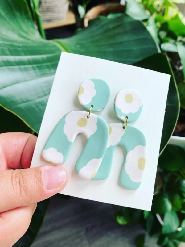 Ceramic earrings held in front of outdoor plants