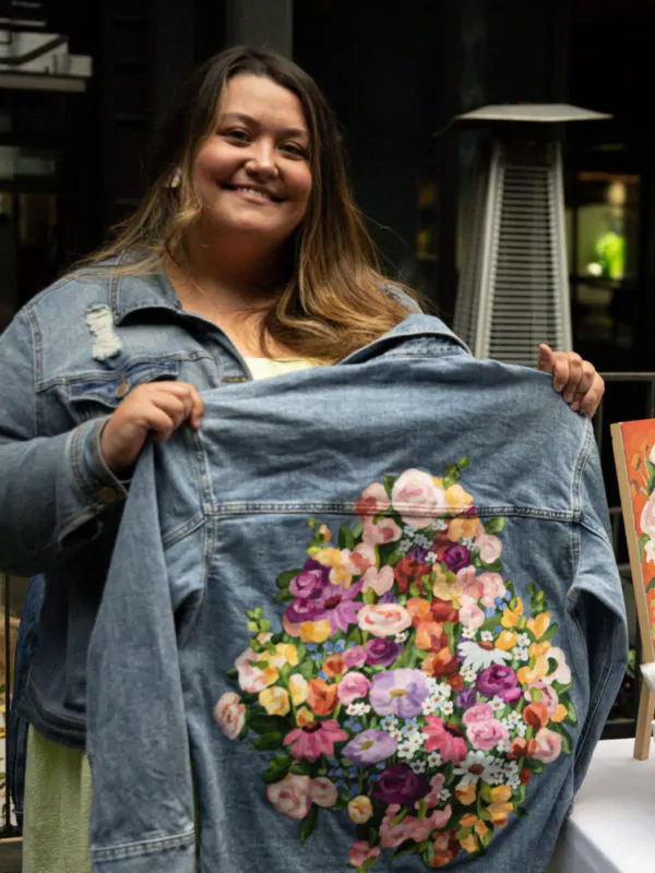 woman holding a painted jean jacket at dairy block denver