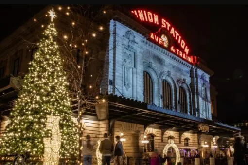Denver Union Station lit with festive Christmas lights, large illuminated tree, and people walking nearby