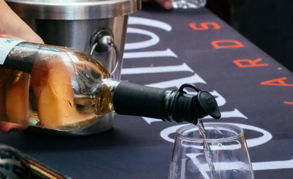 Pouring white wine into a glass on a table at a wine tasting event