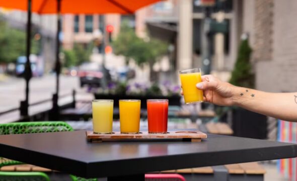 Four colorful juice glasses on table, outdoor cafe setting