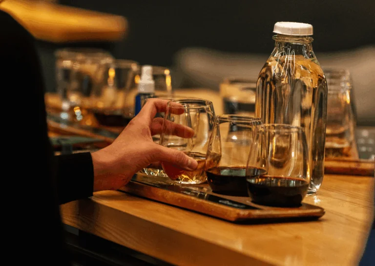 Person extending hand toward wine glasses on a wooden tray