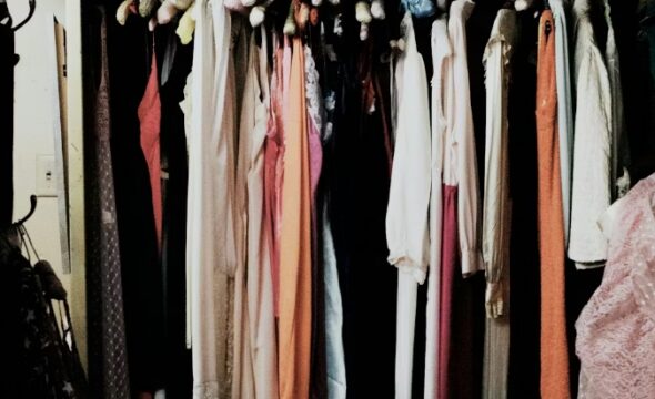 Colorful assortment of dresses hanging in a dimly lit closet