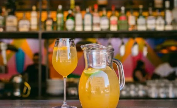 Glass and pitcher of orange juice on bar counter