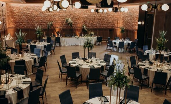 Wedding reception setup with round tables, elegant floral centerpieces, and warm lighting