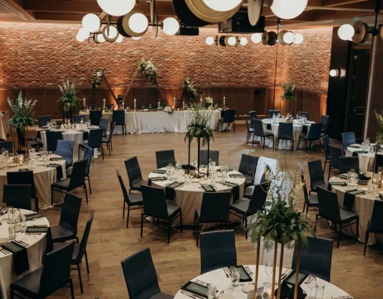 Wedding reception setup with round tables, elegant floral centerpieces, and warm lighting